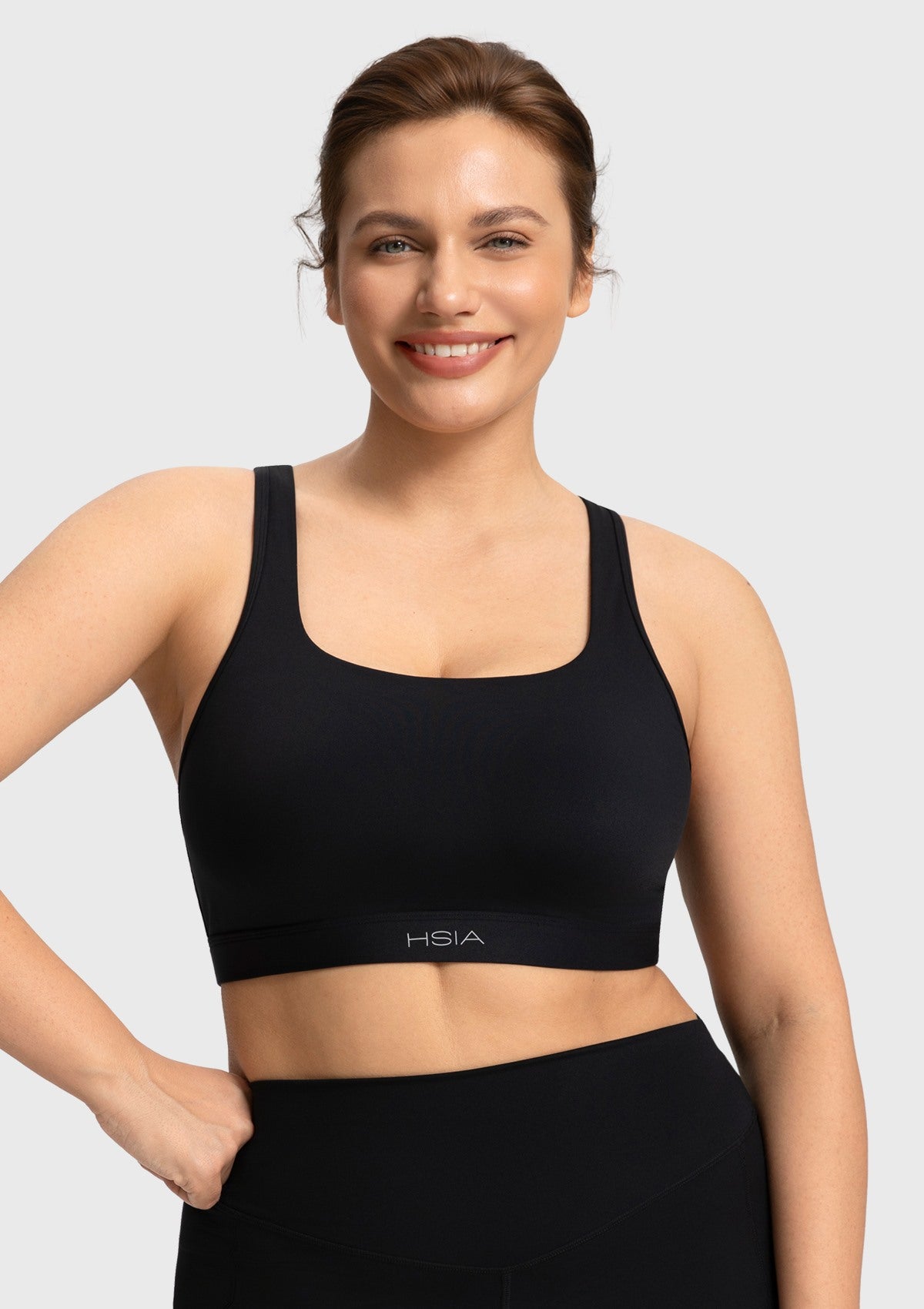Smiling woman wearing the black Aura sports bra highlighting the flattering full coverage fit