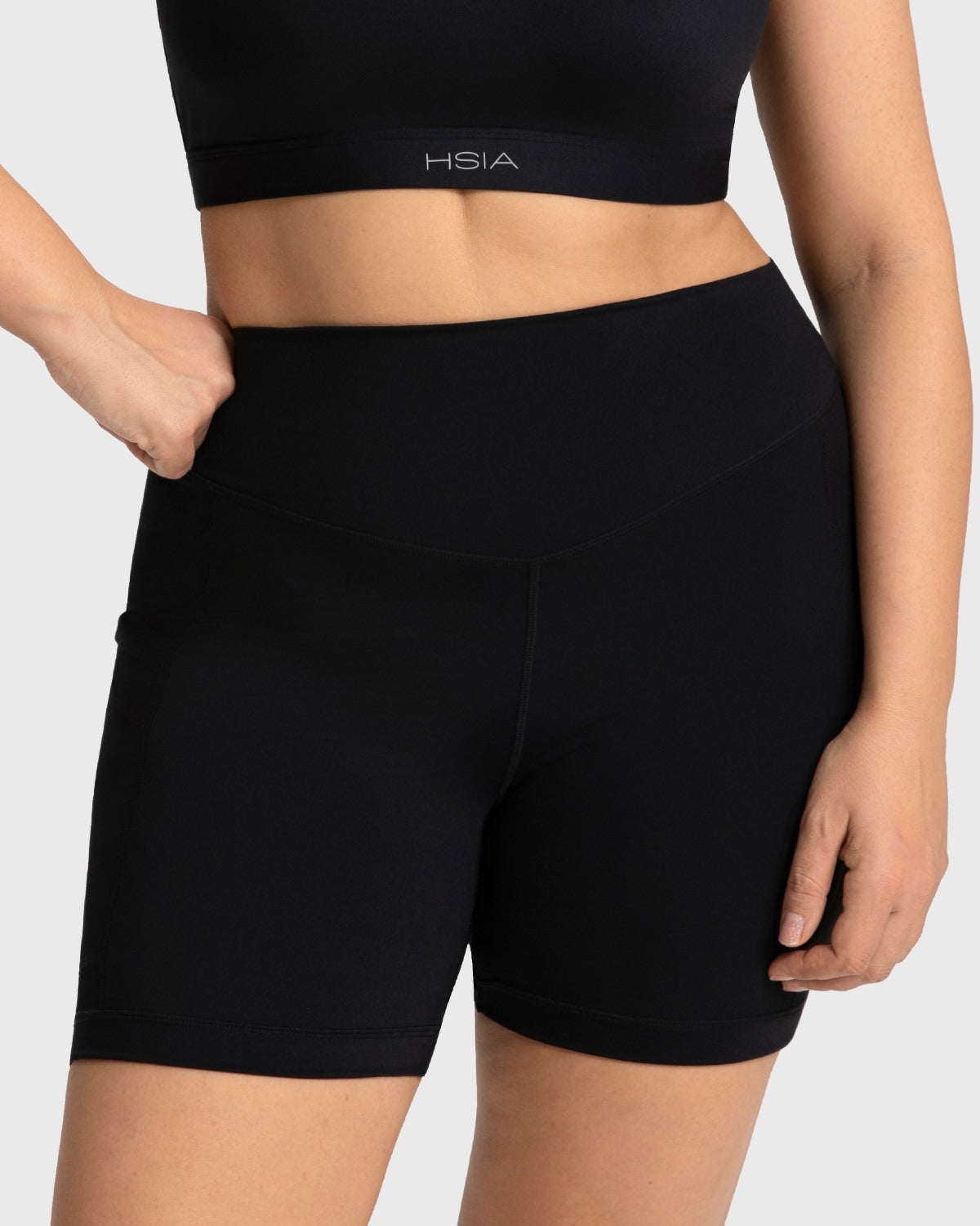 Woman standing with her hands resting comfortably in the deep exterior pockets of the black cycling shorts, perfect for carrying your phone.