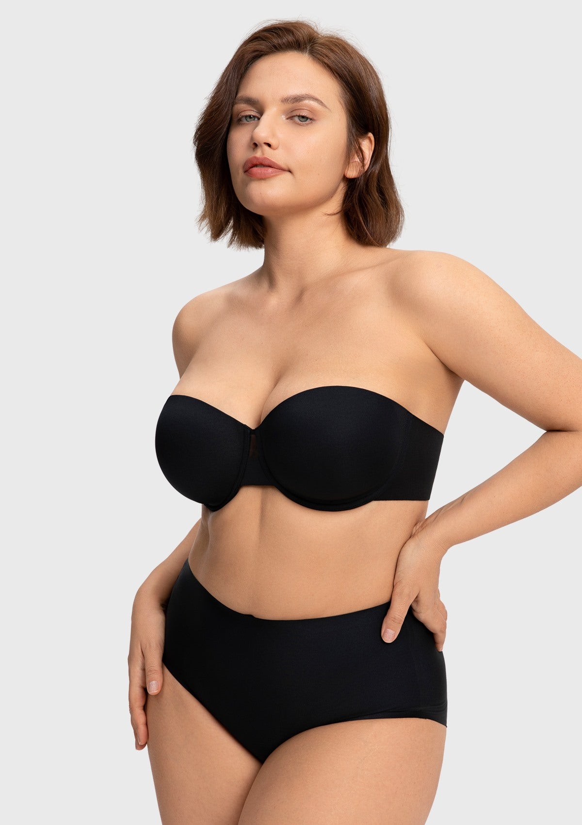 Woman with hands on hips wearing the black strapless bra for a bigger chest, enjoying weightless, breathable, and secure support.