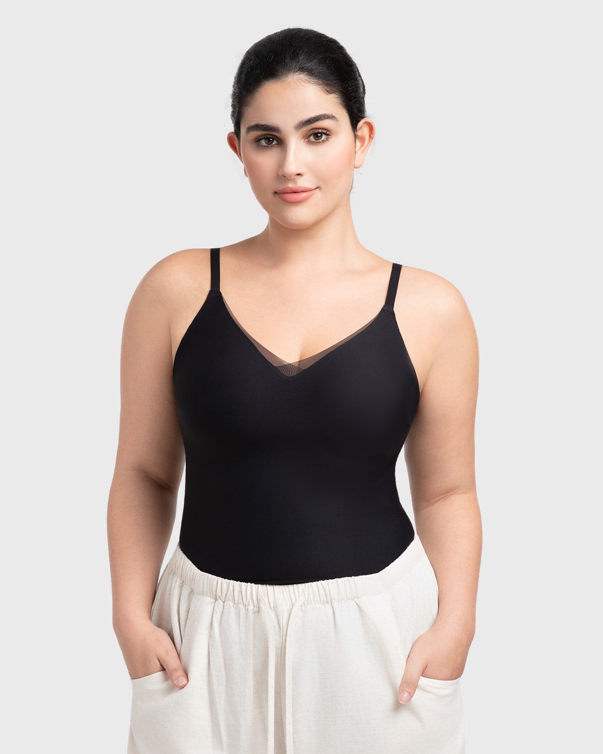 Model styling the black padded camisole as a chic minimalist top tucked into high-waisted pants for an effortless everyday outfit.