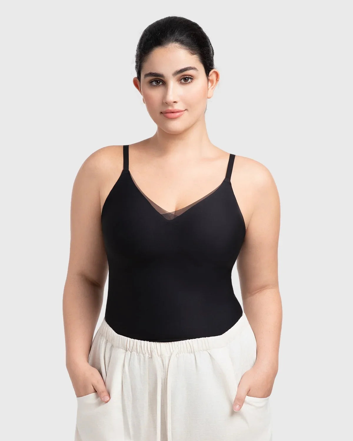 Model styling the black padded camisole as a chic minimalist top tucked into high-waisted pants for an effortless everyday outfit.