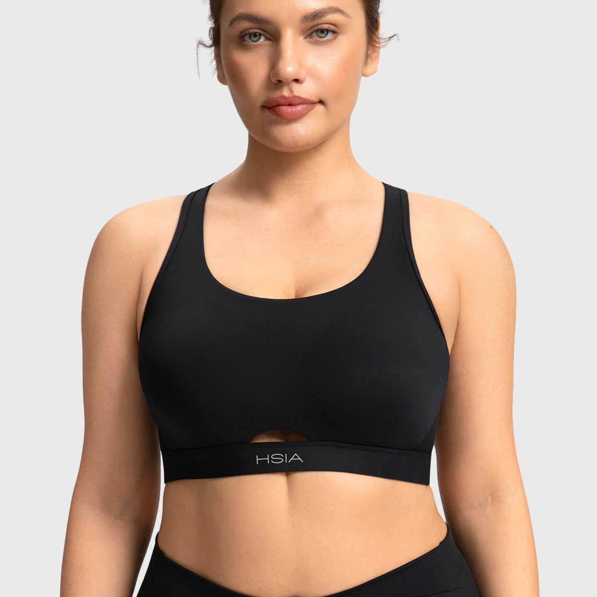Front view of woman wearing the black Aura criss-cross sports bra with keyhole cutout