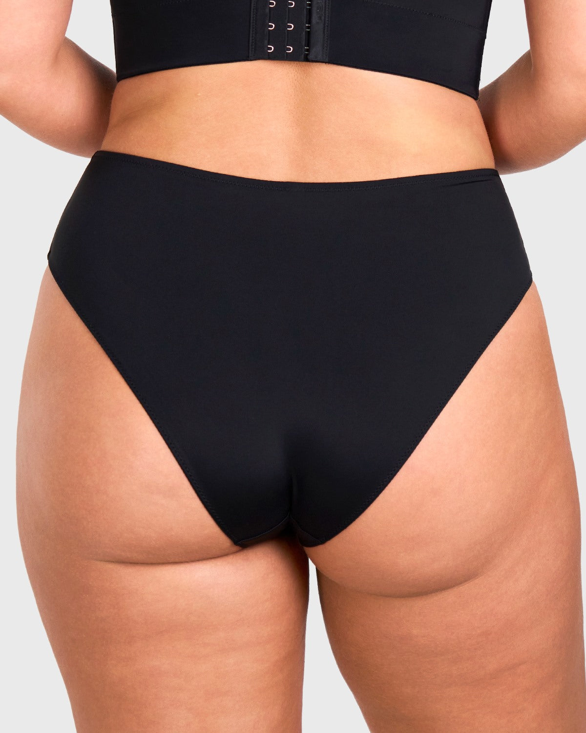 Rear view of model in the black high waist seamless underwear, showcasing full back coverage and no visible panty lines under tight yoga pants.