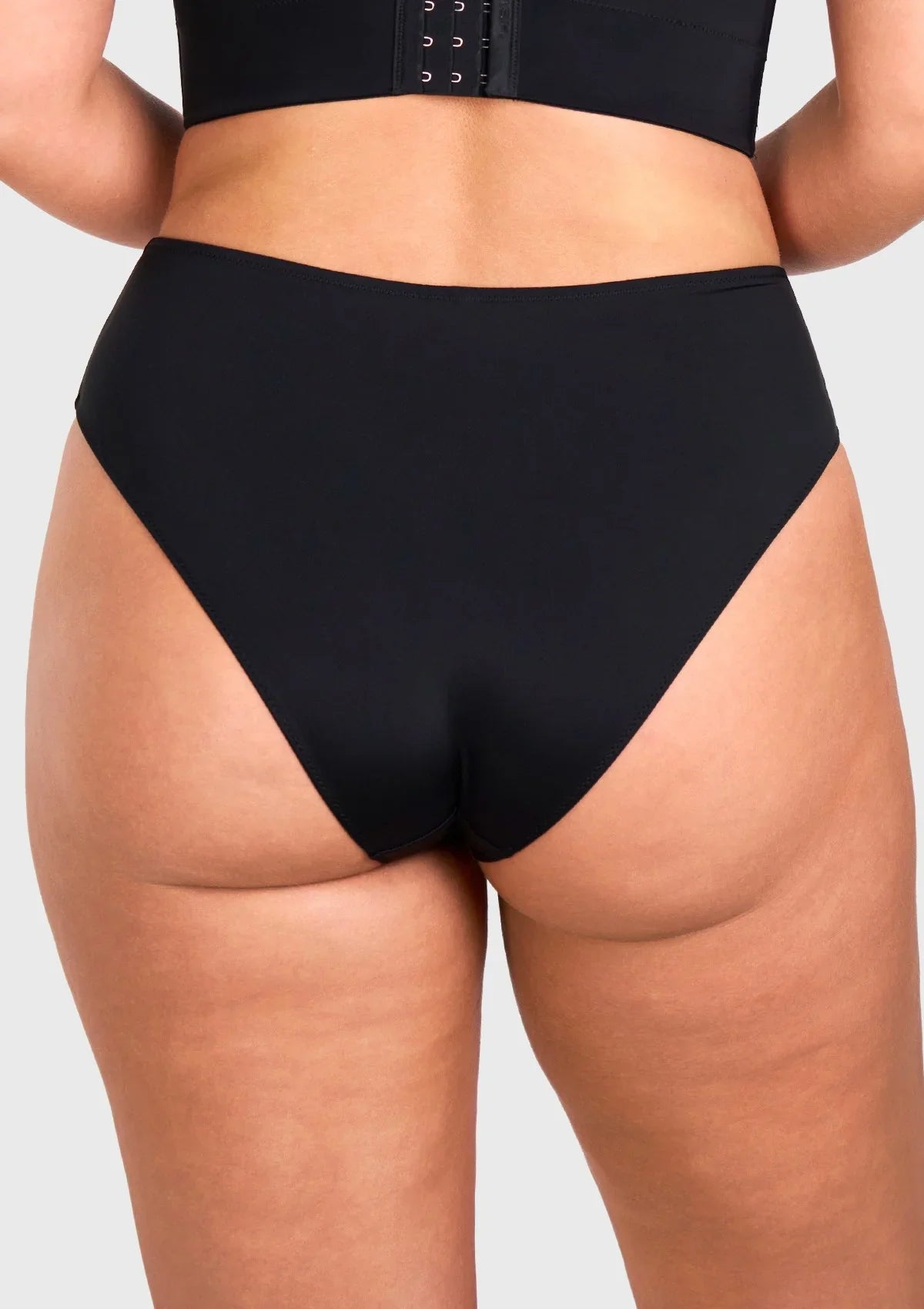 Rear view of model in the black high waist seamless underwear, showcasing full back coverage and no visible panty lines under tight yoga pants.