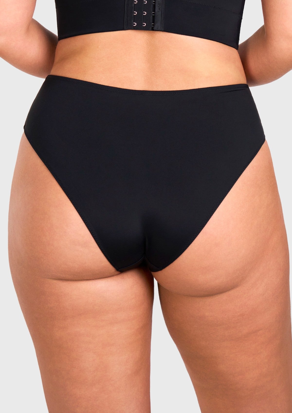 Rear view of model in the black high waist seamless underwear, showcasing full back coverage and no visible panty lines under tight yoga pants.
