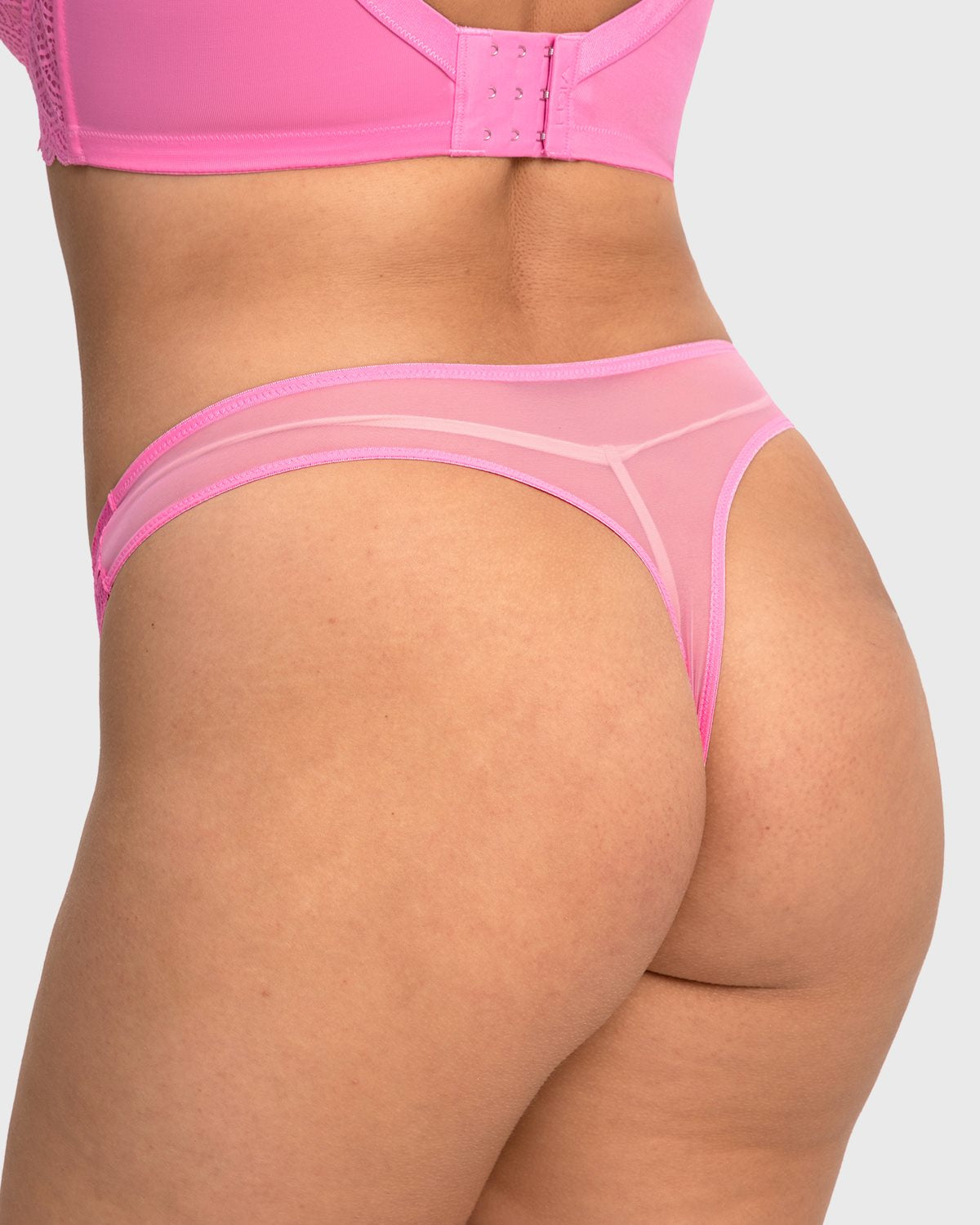 Rear view of model in medium pink high waist lace thong, showcasing a cheeky seamless cut with no visible panty lines under clothes.