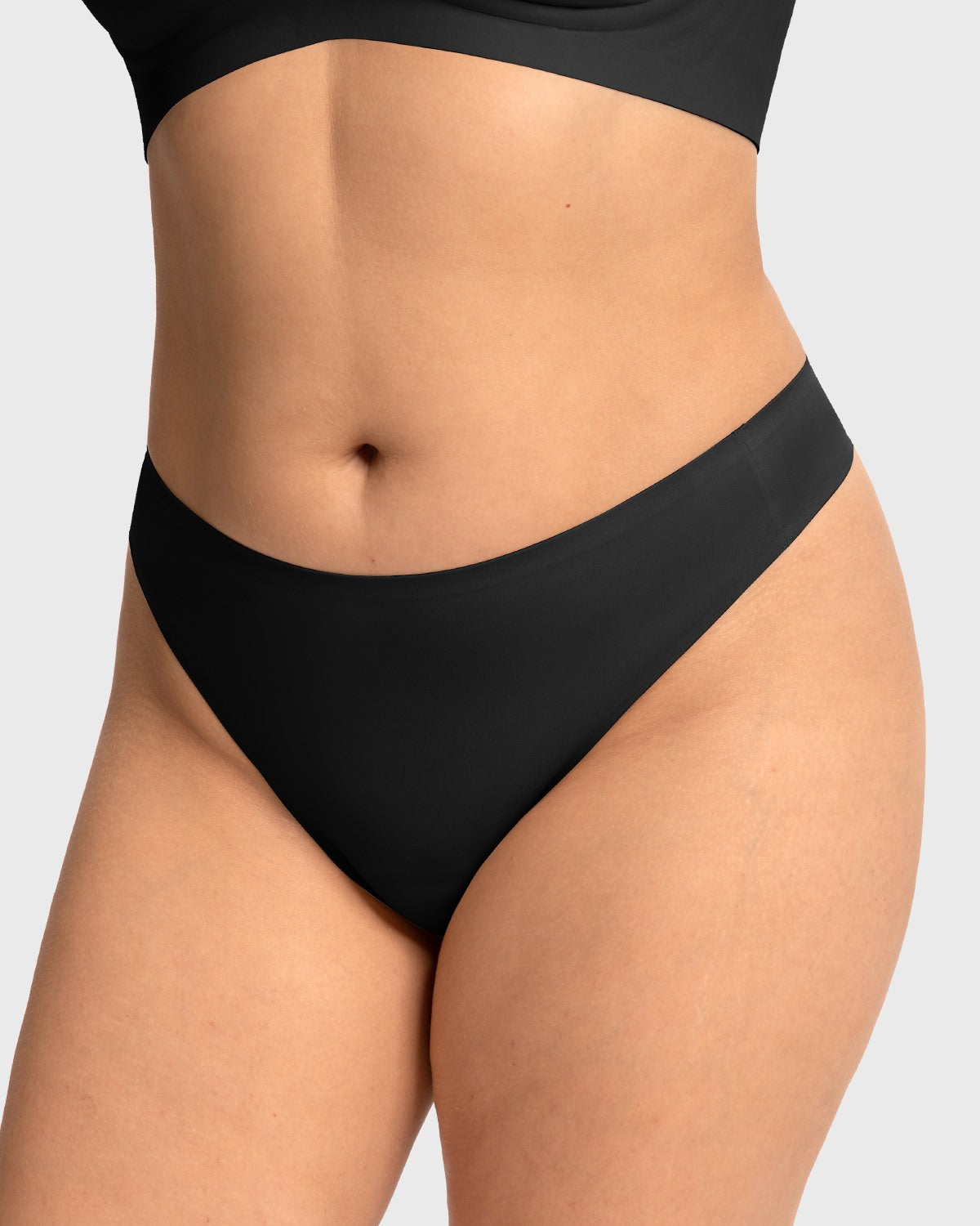 Front view of model wearing the black HSIA SmoothFit seamless thong, featuring a built-in cotton pad to prevent camel toe under tight leggings.