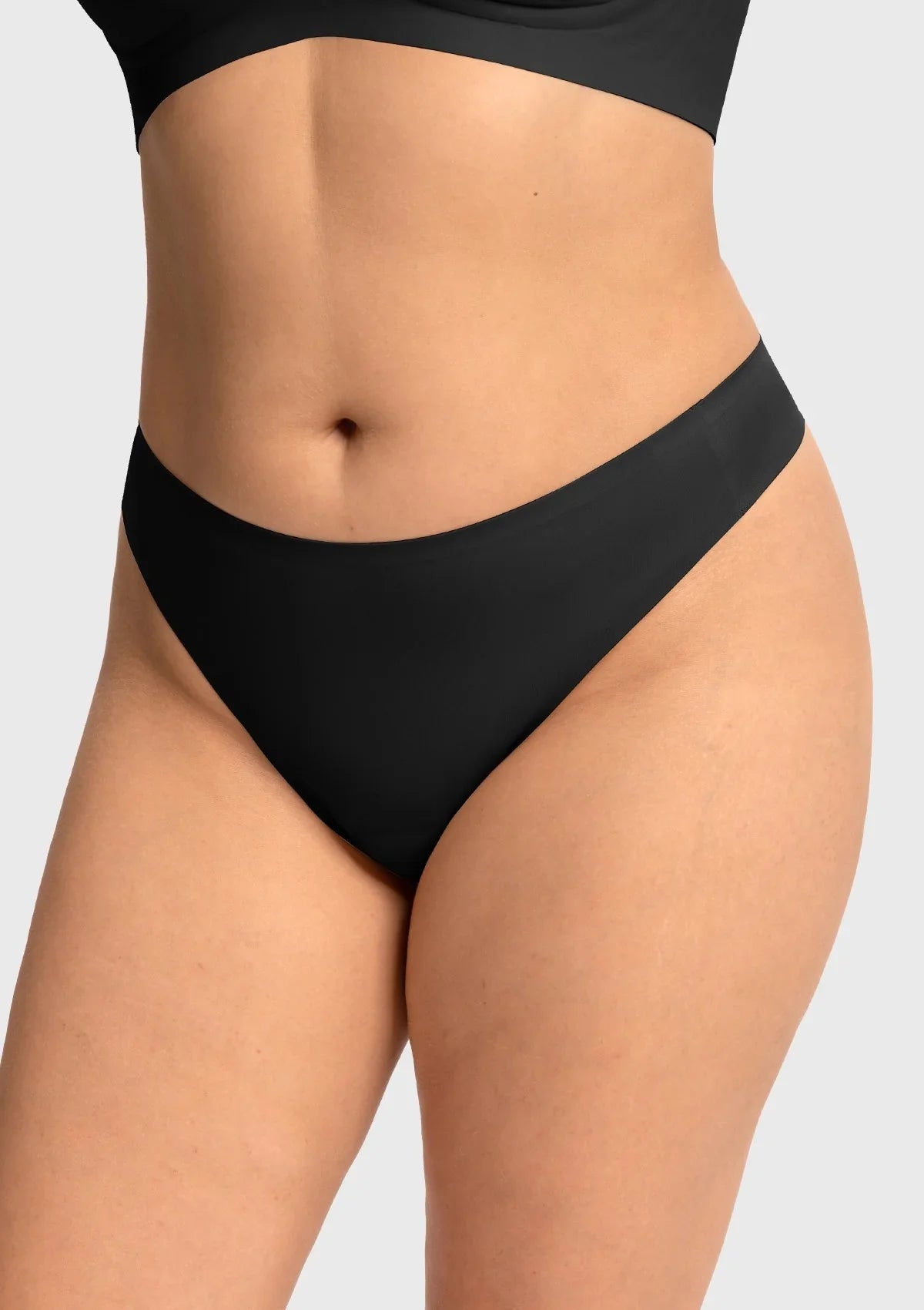Front view of model wearing the black HSIA SmoothFit seamless thong, featuring a built-in cotton pad to prevent camel toe under tight leggings.