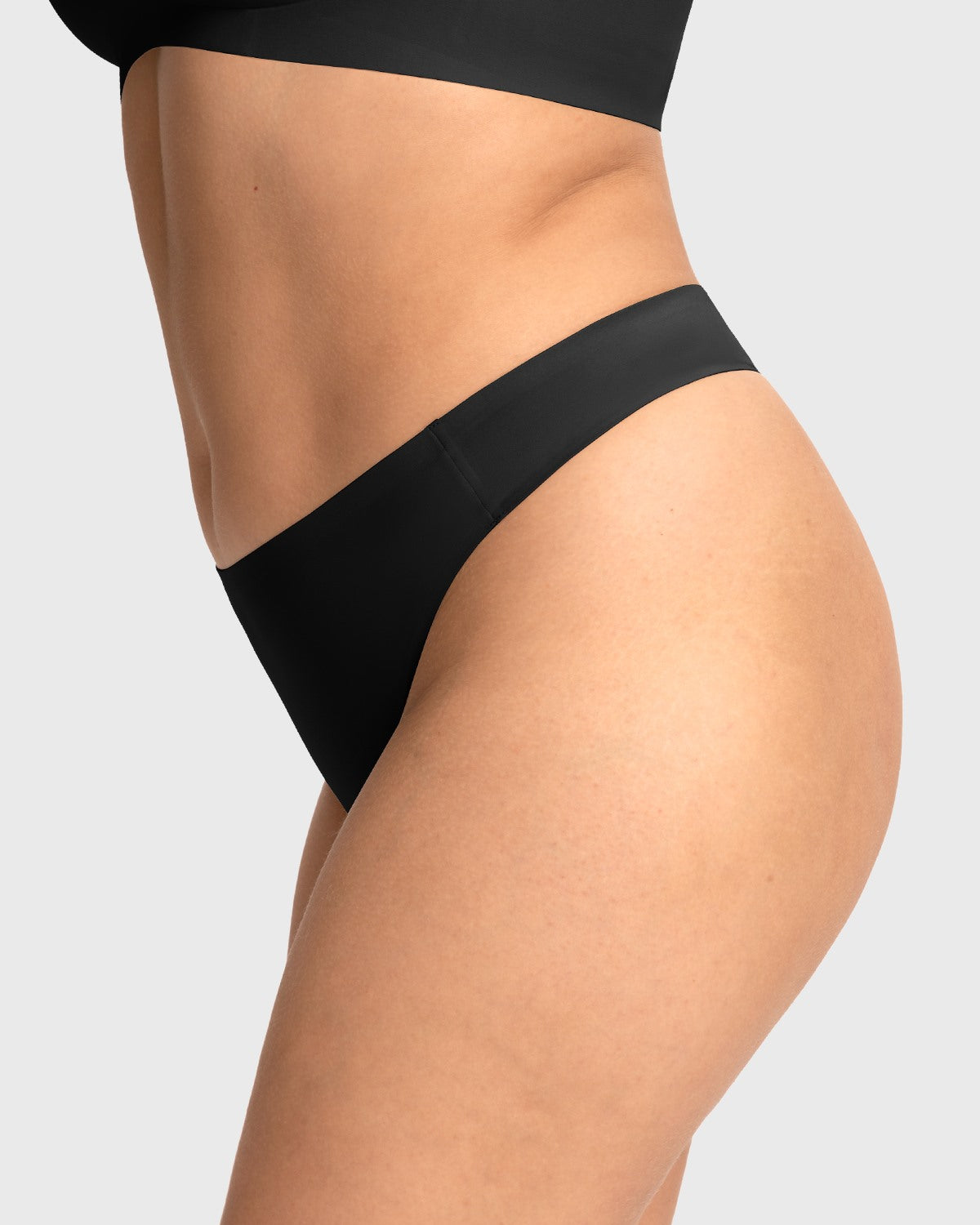 Side profile of model in the black seamless thong, highlighting the no-show edges that create an invisible look under biker shorts.