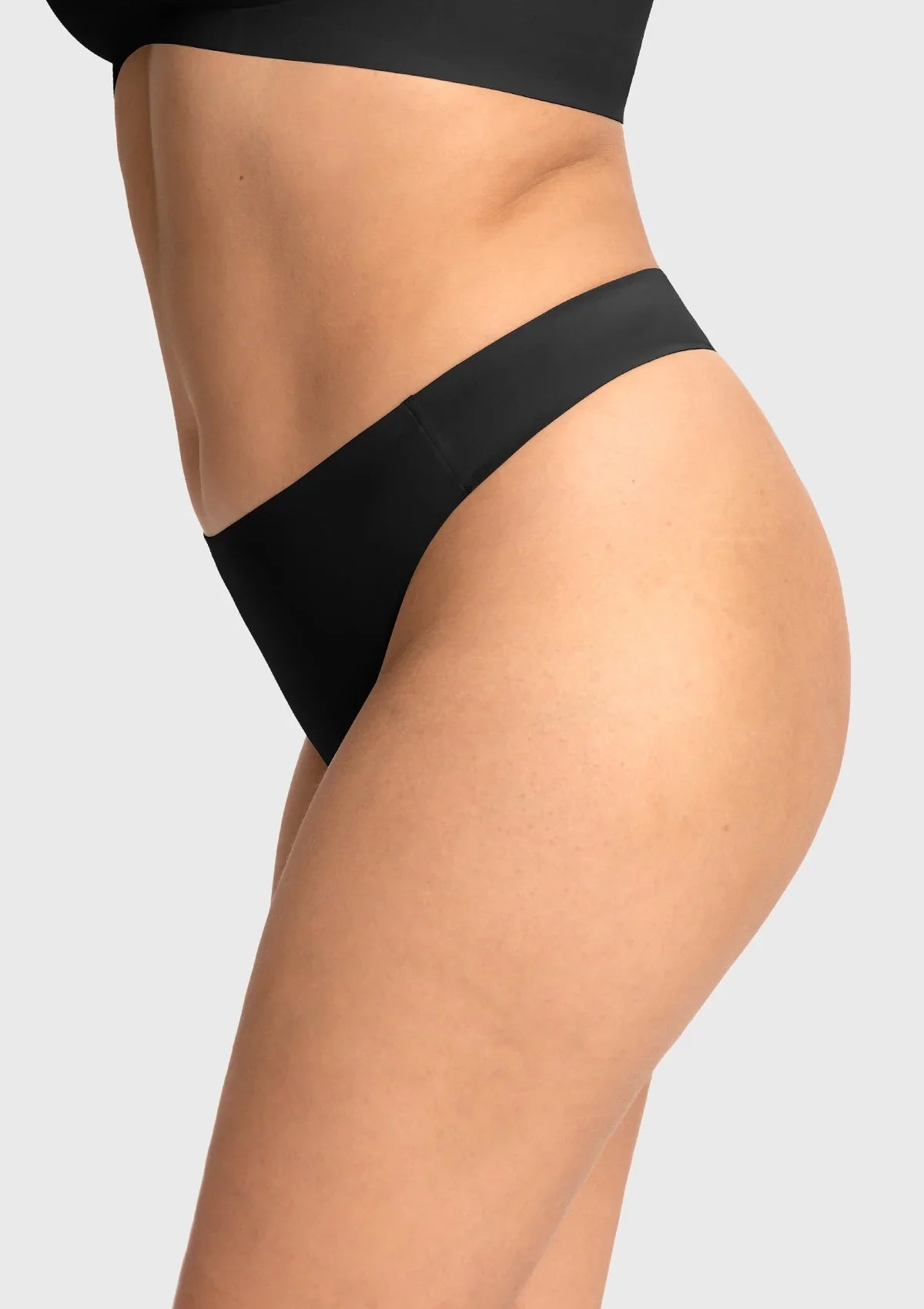 Side profile of model in the black seamless thong, highlighting the no-show edges that create an invisible look under biker shorts.