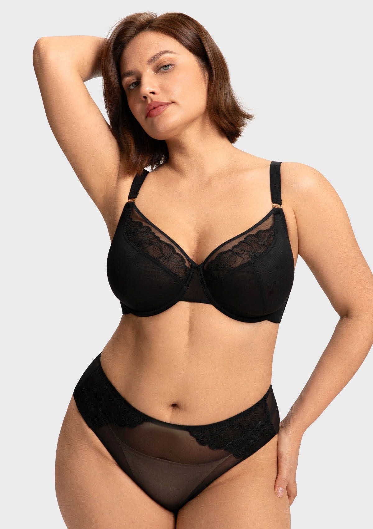 Confident model with raised arms wearing the black Yumi unlined bra, showcasing perfect containment and an underwire that stays securely in place.