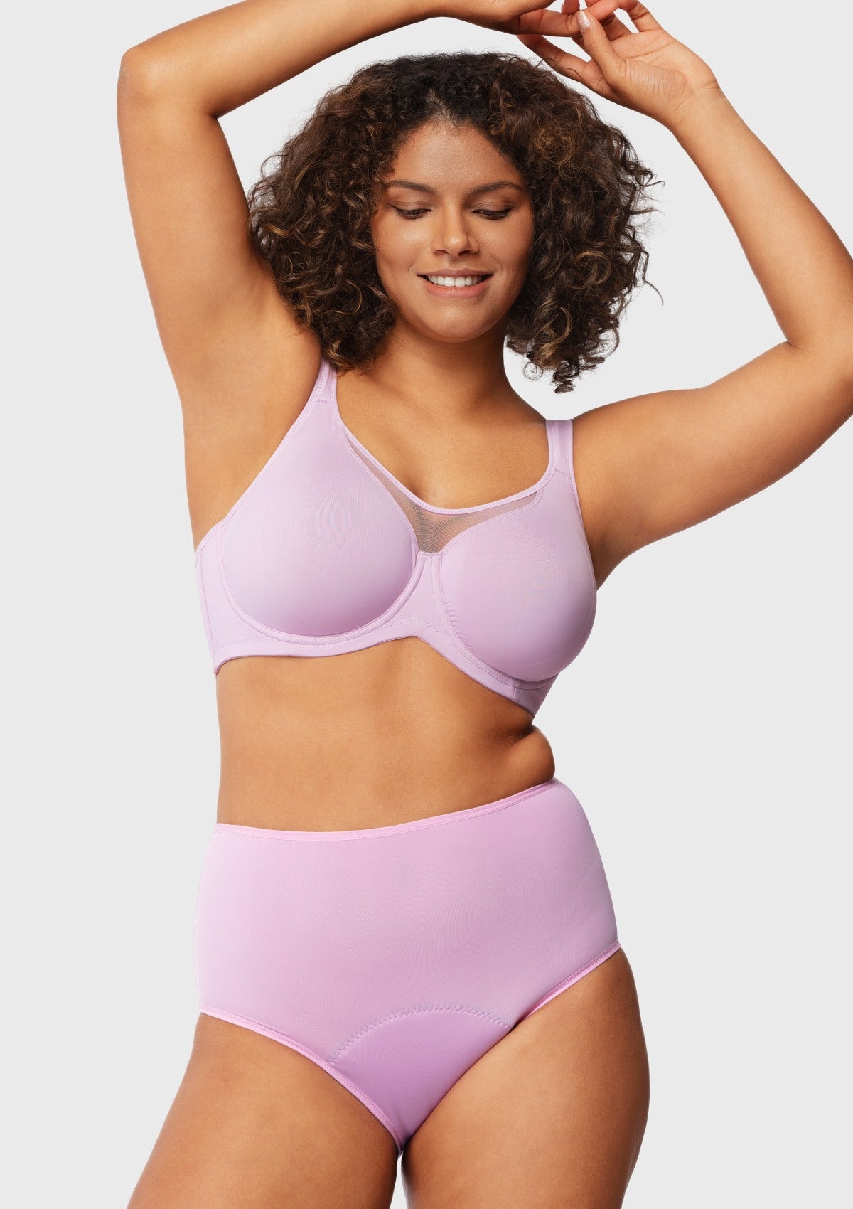 Woman raising her arms in the lavender minimizer bra, showing how the patented flexible underwire lifts securely without digging or poking.