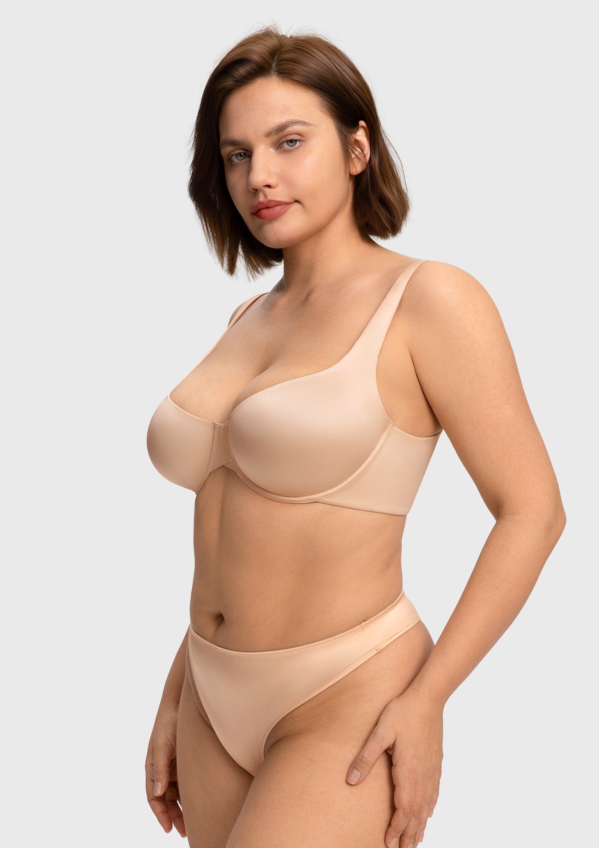 Confident woman with hands on hips wearing the light beige seamless balconette bra, highlighting the flattering criss-cross center gore and second-skin fit.