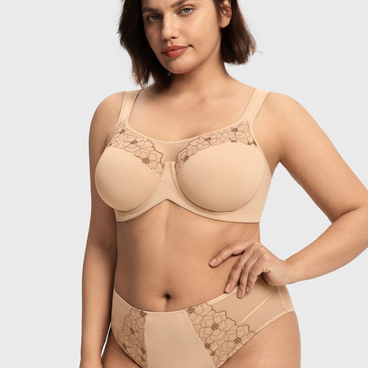 Confident woman with hands on hips wearing the light beige unlined bra for large busts, showcasing the spill-free sheer mesh neckline.