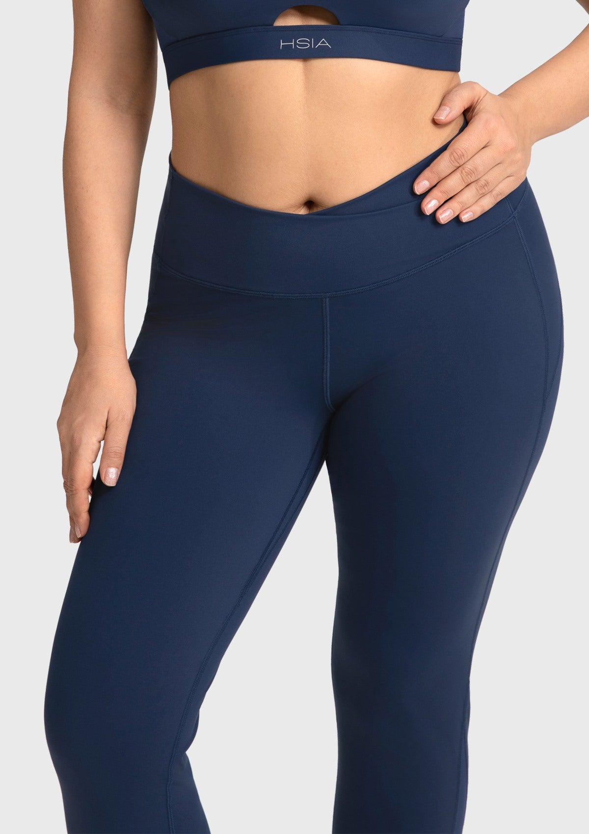 Detailed close-up of the navy blue slimming leggings, focusing on the chic V-shaped crossover waistline that provides gentle tummy control.