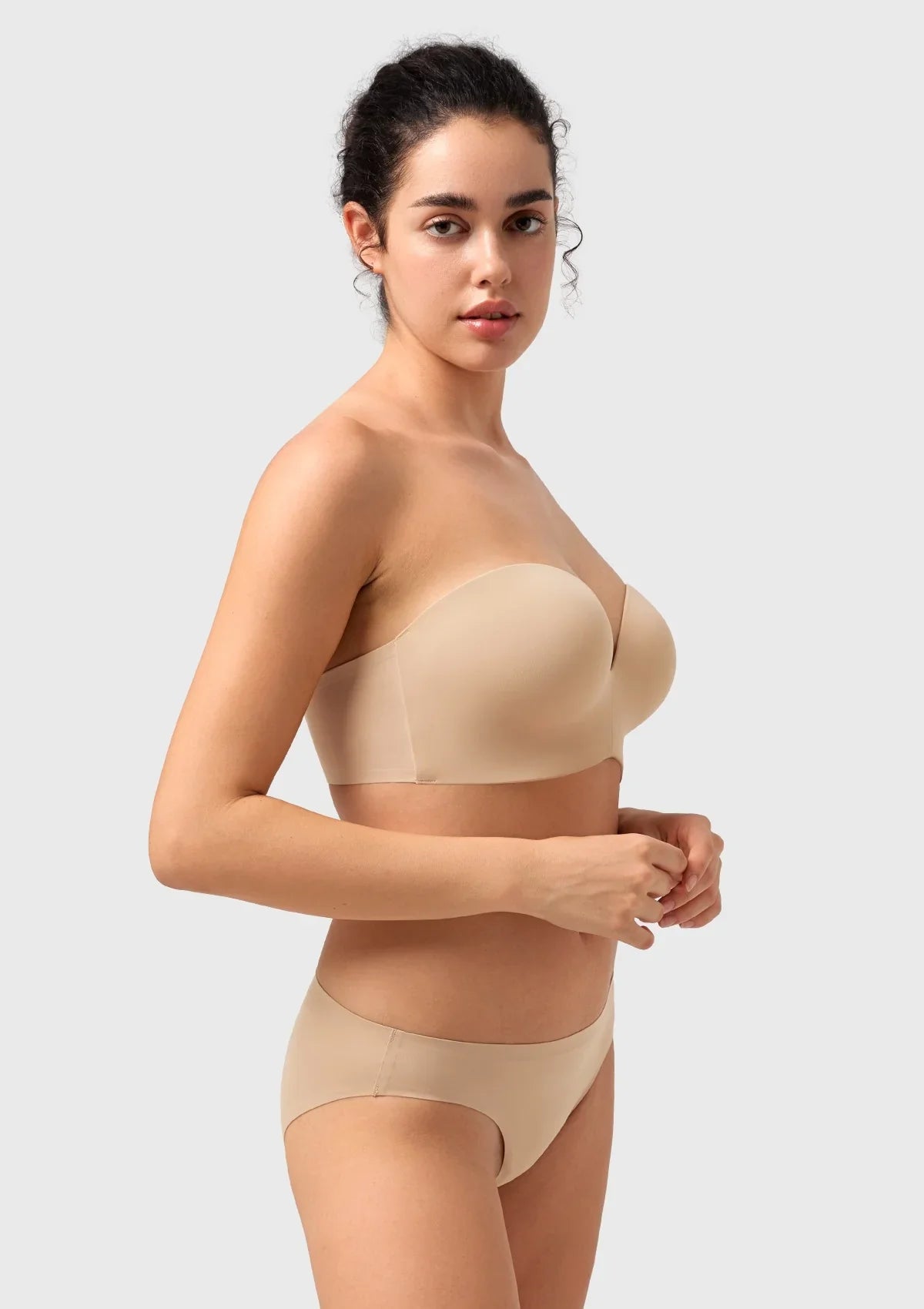 Woman with raised arms demonstrating the stay-put bonded wings of the nude seamless strapless bra for all-day security.