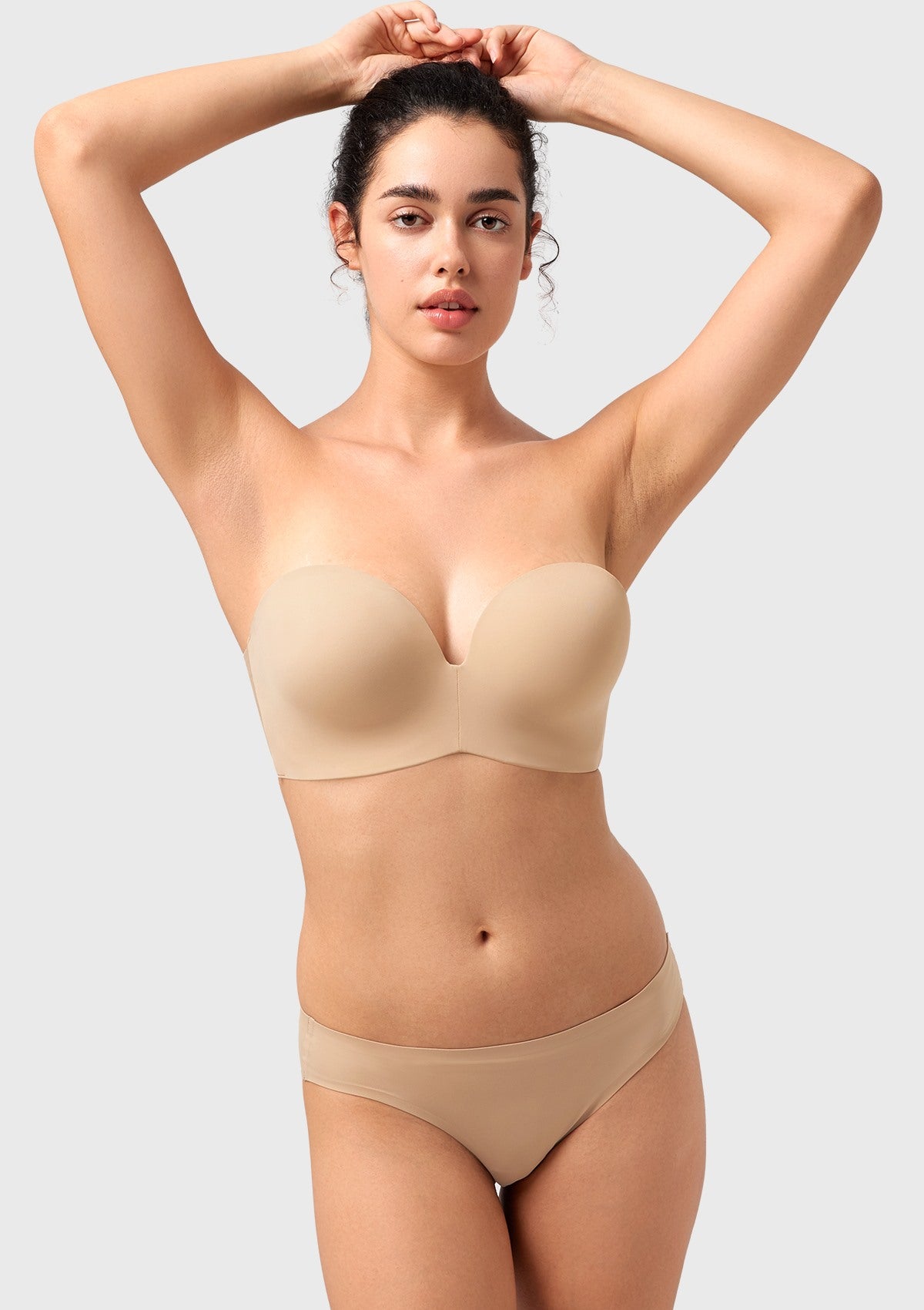 Woman raising her arms wearing the most comfortable strapless bra that stays up, highlighting its secure anti-slip technology without digging in.