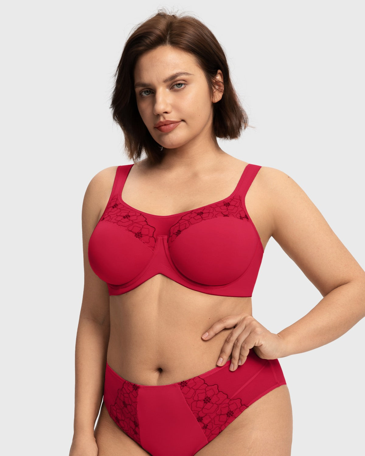 Woman with hands on hips modeling the red supportive unlined lace bra, enjoying a lightweight feel with the unwavering stability of a sports bra.