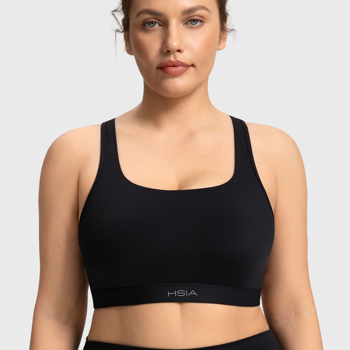 Front view of woman wearing the black Aura medium support cooling sports bra
