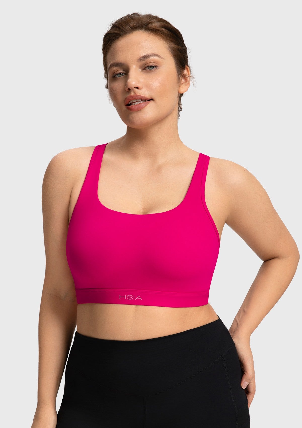 Front view of woman wearing the vibrant dragon fruit pink Aura medium support sports bra