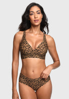 A woman modeling a leopard-print two-piece bikini set against a light gray studio background. The set includes a V-neck bralette top and matching high-waisted briefs in a brown and black animal print pattern.