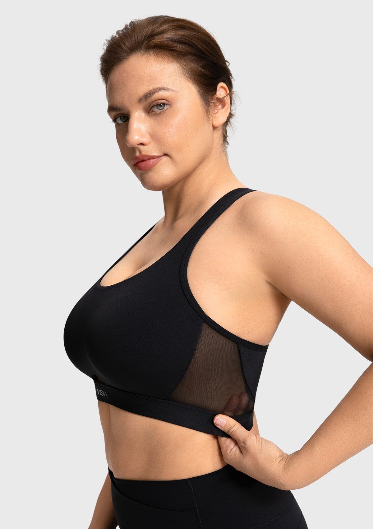 Side profile of the black Aura workout top highlighting breathable mesh side panels
