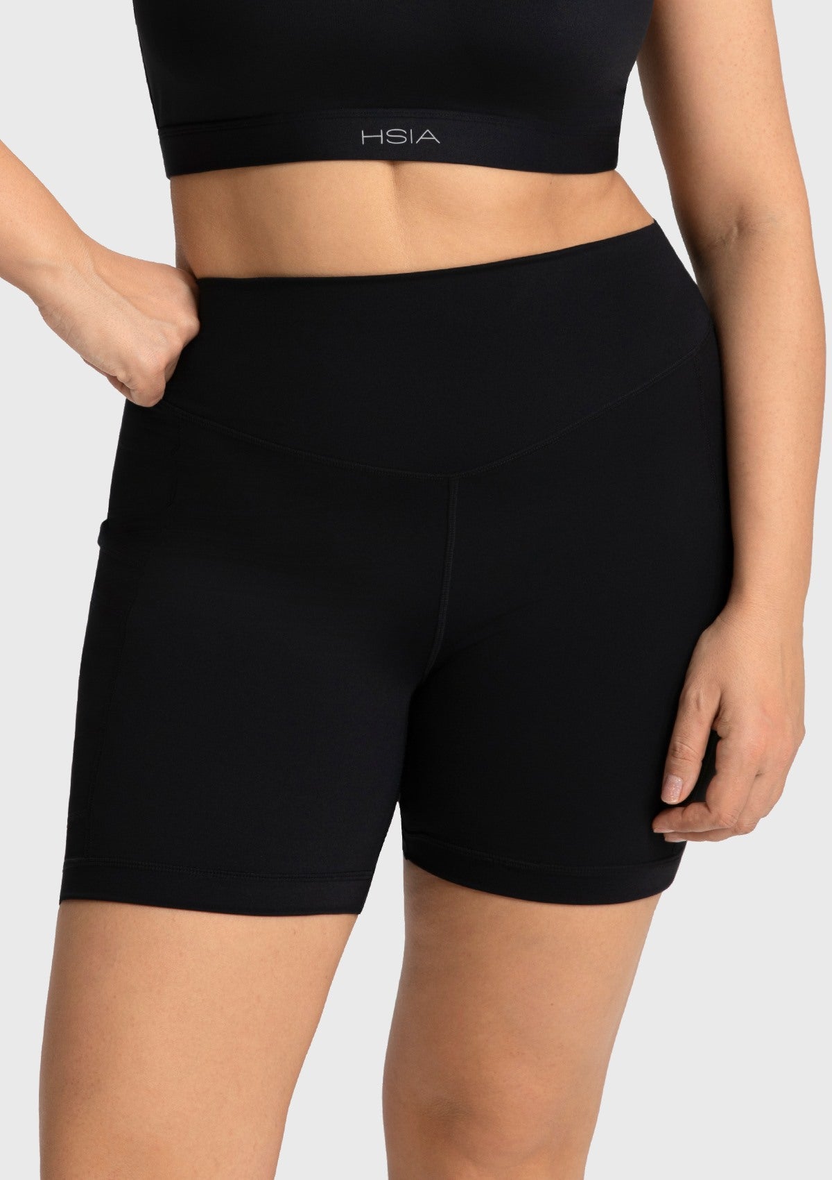 Woman standing with her hands resting comfortably in the deep exterior pockets of the black cycling shorts, perfect for carrying your phone.