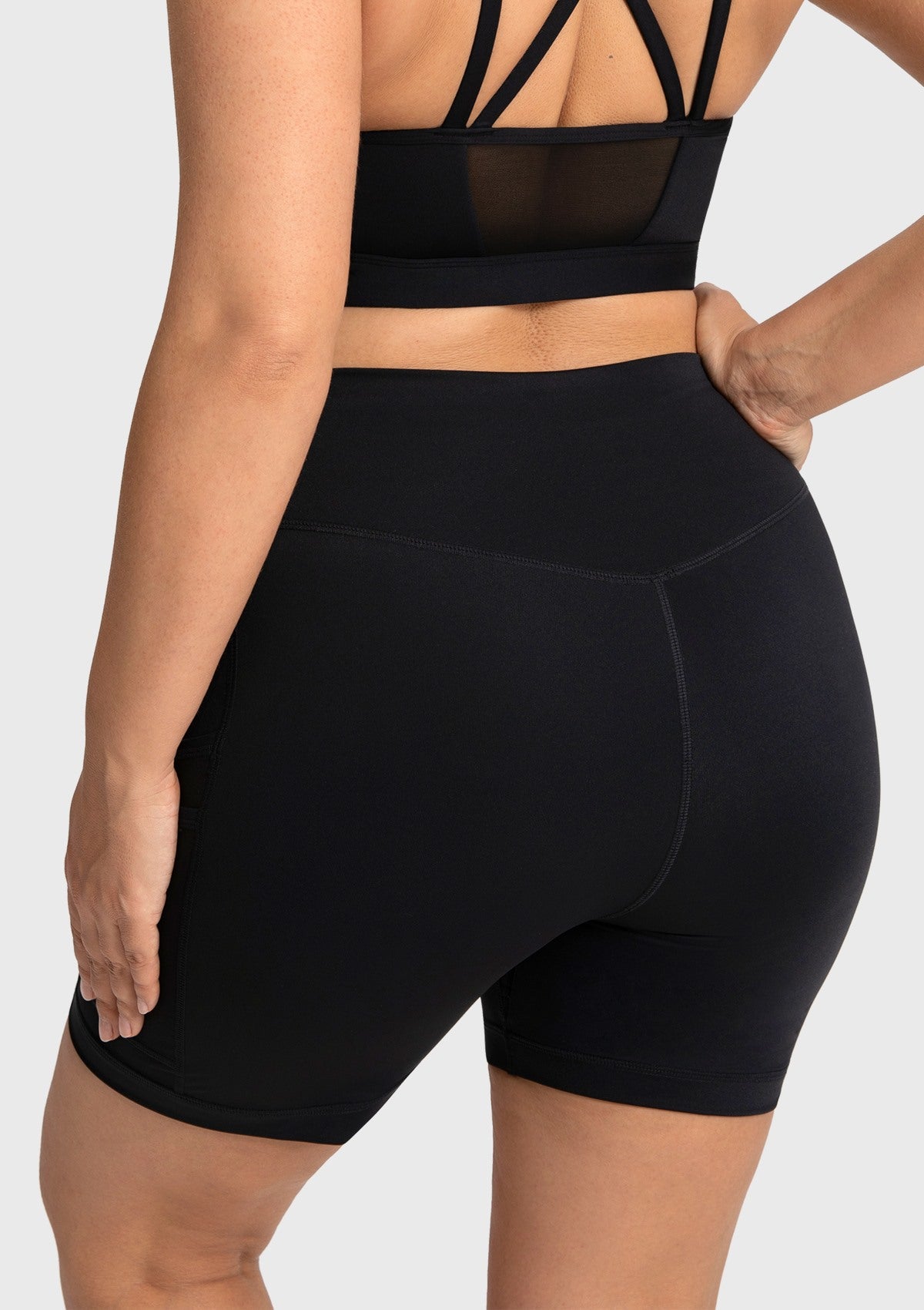 Back view of the black squat-proof biker shorts, demonstrating a secure, high-rise fit with excellent glute coverage while keeping hands in pockets.