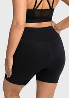 Back view of the black squat-proof biker shorts, demonstrating a secure, high-rise fit with excellent glute coverage while keeping hands in pockets.
