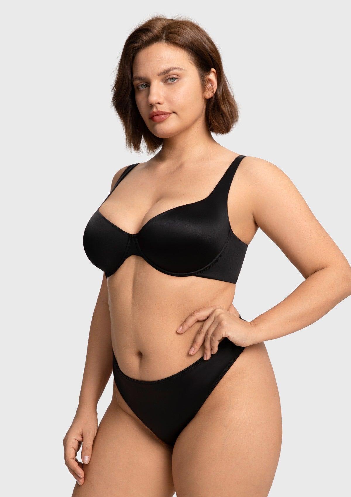 Side profile of the black stretch satin everyday bra on a woman with hands on hips, demonstrating perfect contouring and lightweight lift.