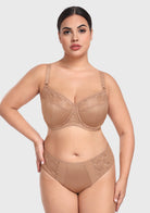  Confident woman with hands on hips wearing the dark beige unlined balconette bra, featuring a natural, rounded lift and perfect separation.