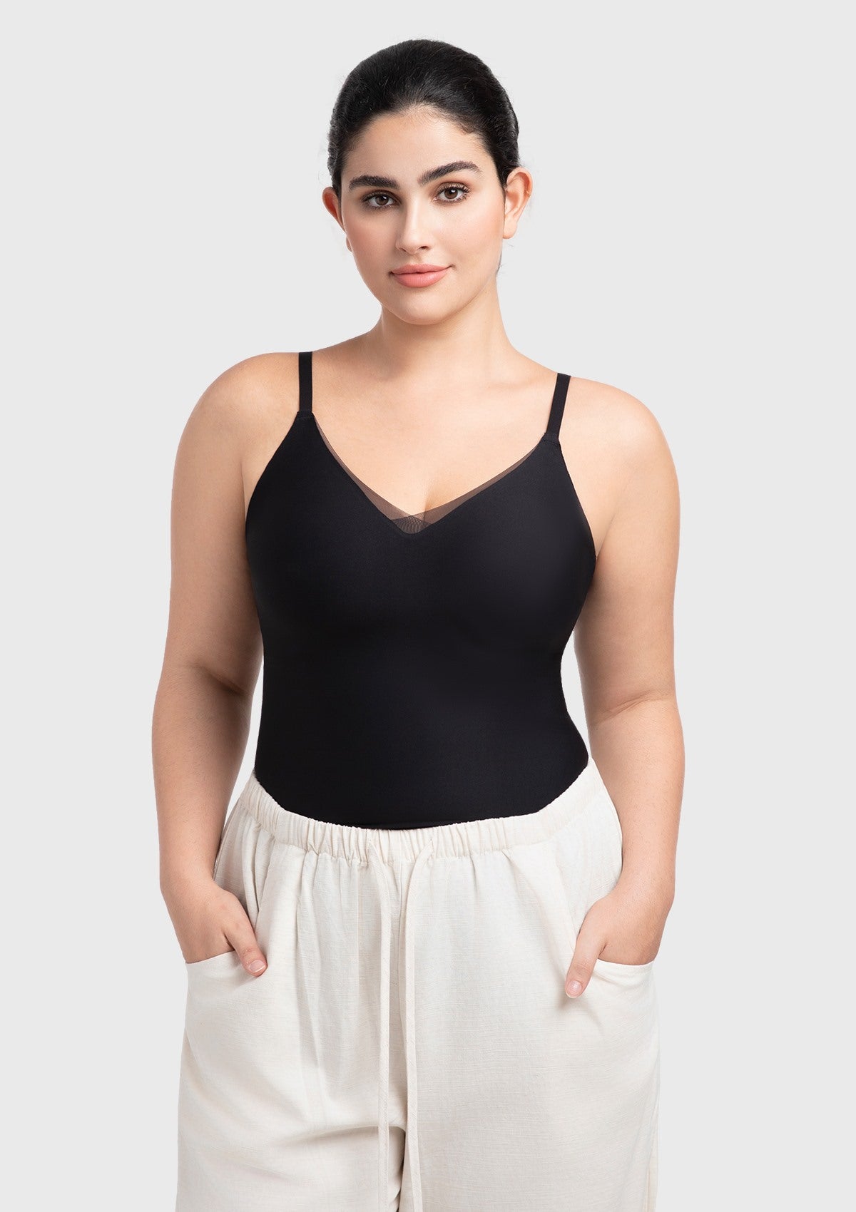 Model styling the black padded camisole as a chic minimalist top tucked into high-waisted pants for an effortless everyday outfit.