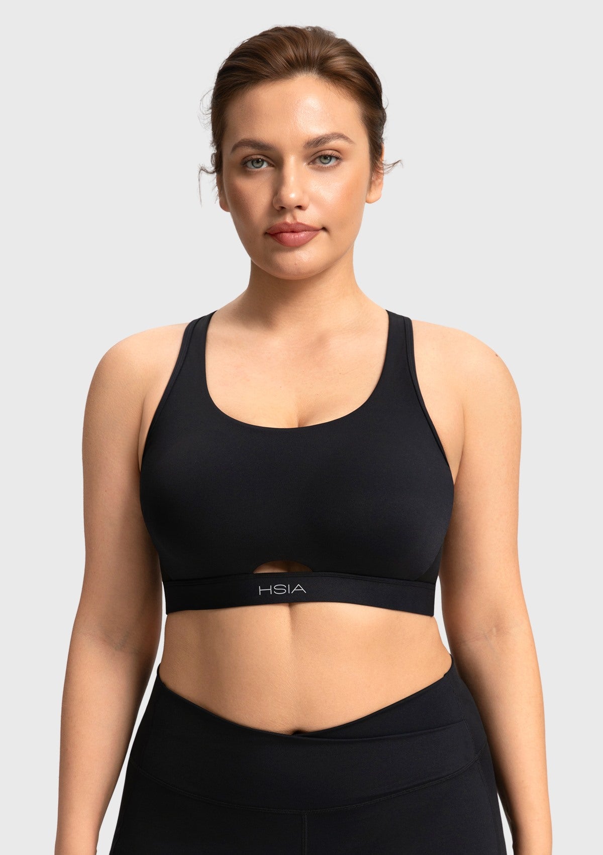 Front view of woman wearing the black Aura criss-cross sports bra with keyhole cutout
