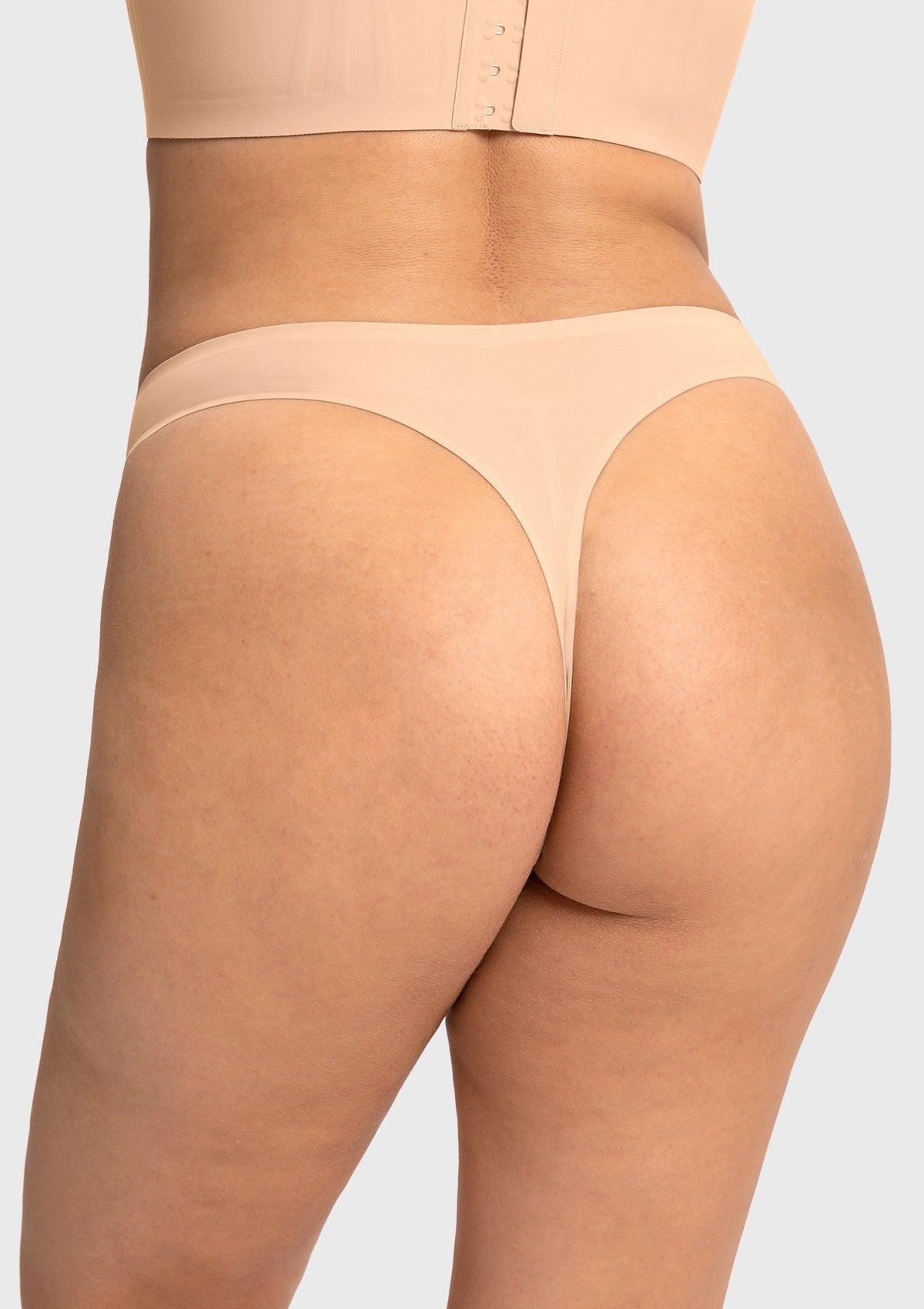 Back view of the beige mid-rise thong, offering comfortable support for hips and a completely invisible look under light-colored clothes.