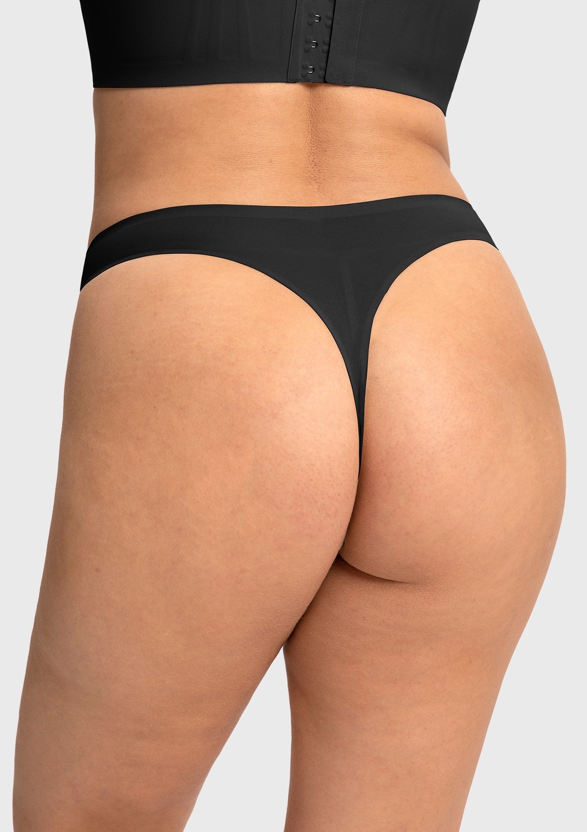 Back view of the black mid-rise thong on model, ensuring zero visible panty lines and a secure, non-slip fit all day.