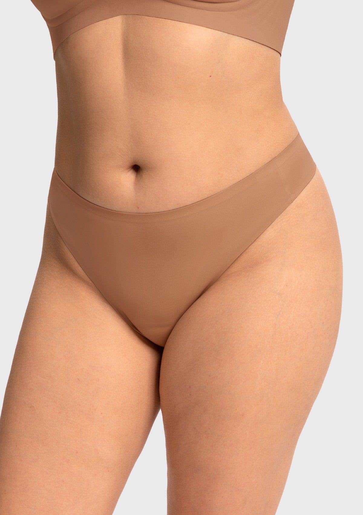 Model wearing the Coffee brown HSIA SmoothFit thong, featuring an invisible front pad for a flawless look in gym wear.