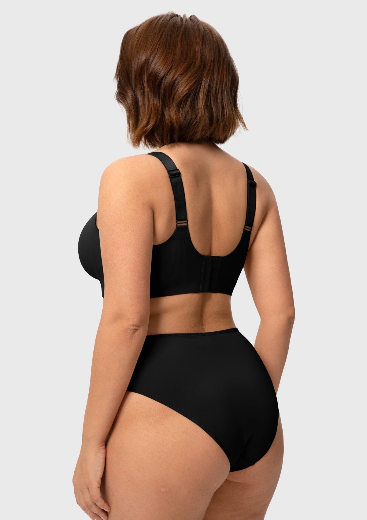 Rear view of the black wireless bra on model, detailing the smoothing wide side panels and secure 4-row hook closure that eliminates back bulges.